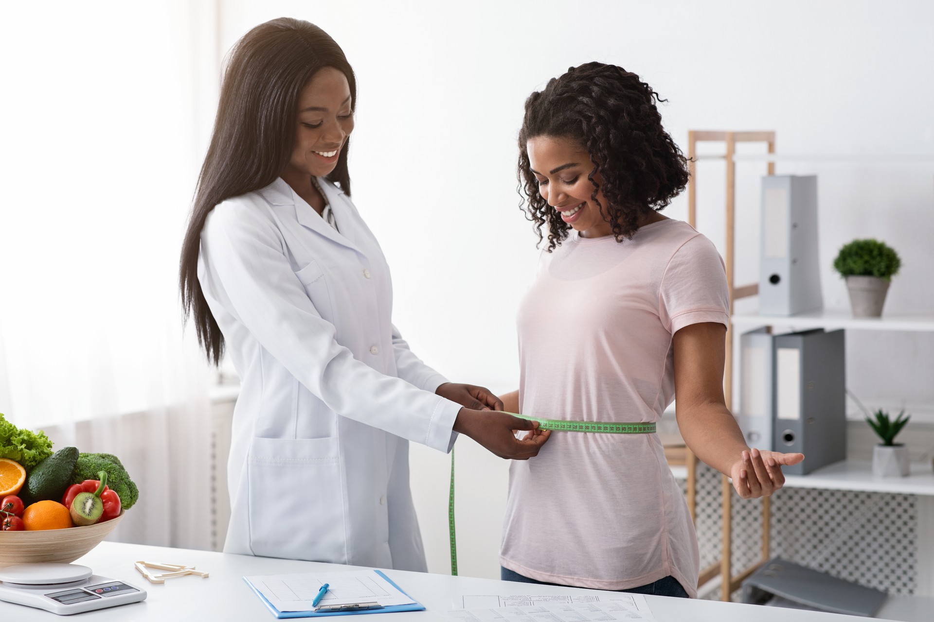 Young black woman taking body measurements at dietologist office