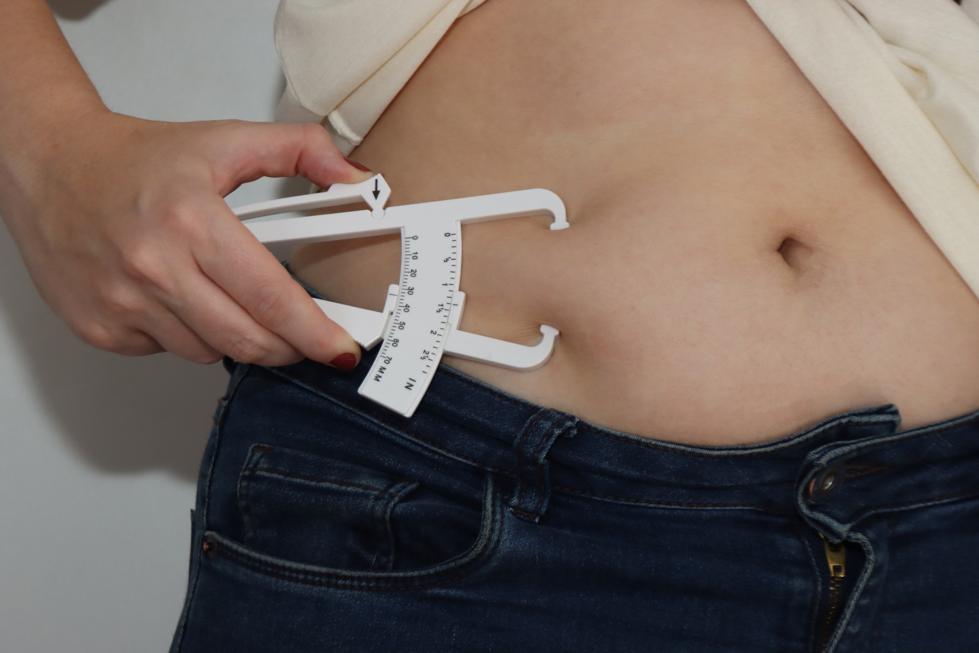 Measuring abdomen fat in a woman with and adipometer skin fold. Close up in the abdomen